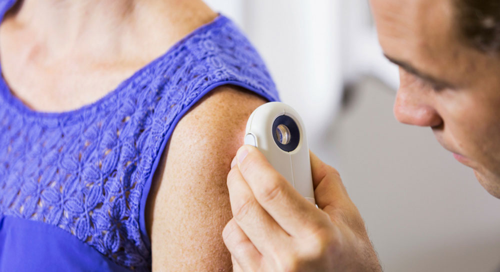 Doctor uses a magnifying glass to inspect a patient's arm