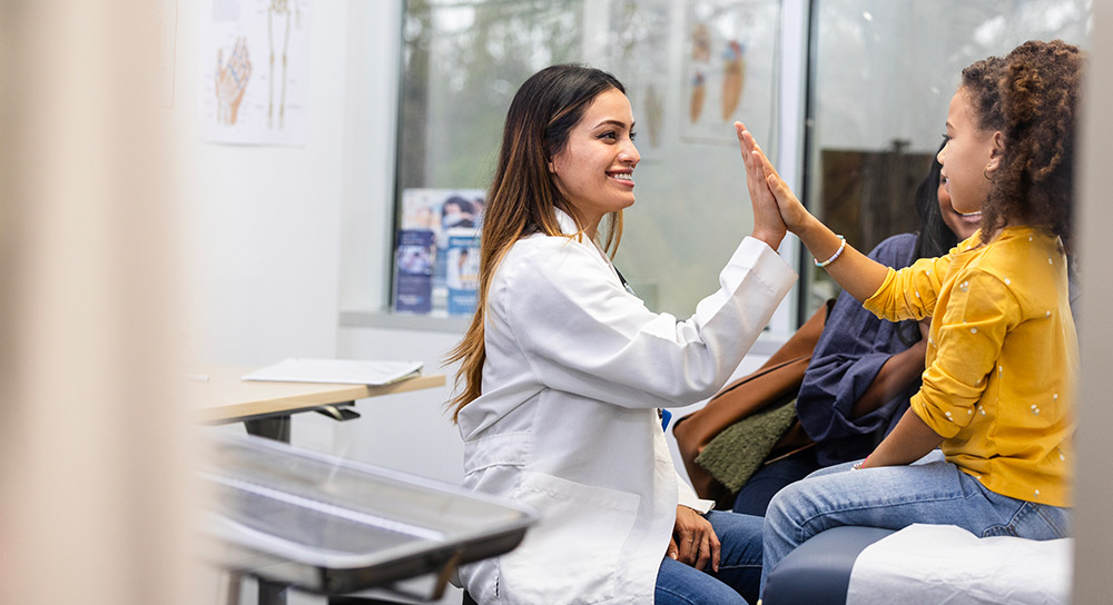 A female doctor high fives a female pediatric patient