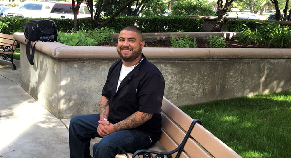 A young man sits outside on a bench