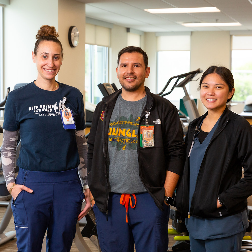 Three physical therapists stand in a gym