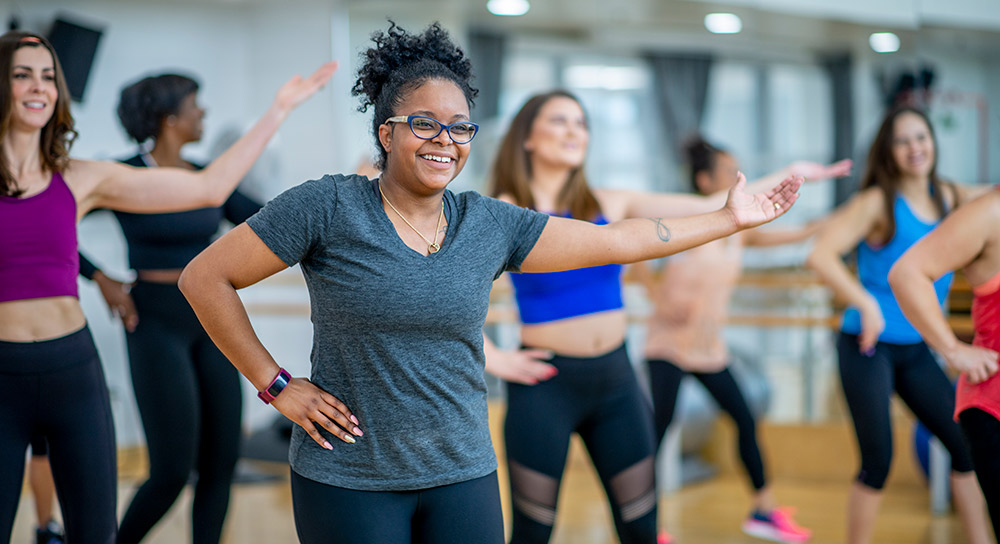 group of women smiling as they go through a group fitness routine