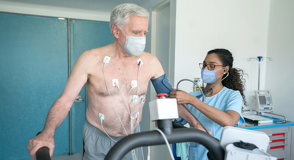 health care professional monitoring a patient on a treadmill with monitors attached to him
