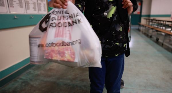 student carring plastic shopping bag full of food