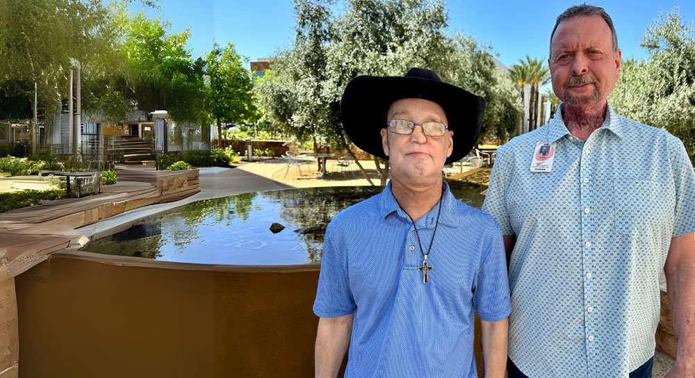 Two men standing outside next to a water feature face the camera