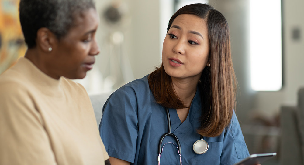 nurse in blue scrubs speaking with her patient