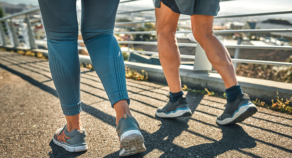 the back of two pairs of legs walking down the street