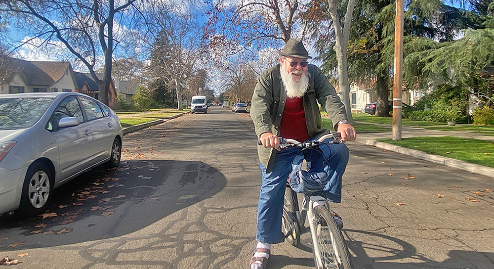A man in a hat sits atop his bicycle on a road