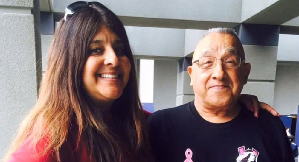 A grown daughter stands next to her father