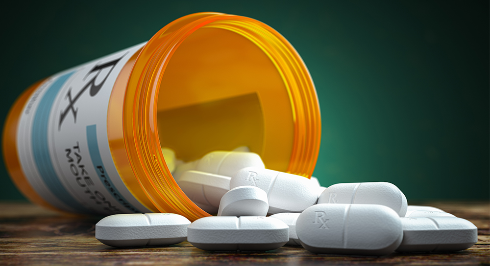 close up view of prescription bottle on its side with generic white pills spilling out