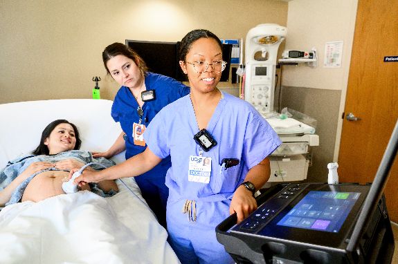 two nurses scanning pregnant women's belly