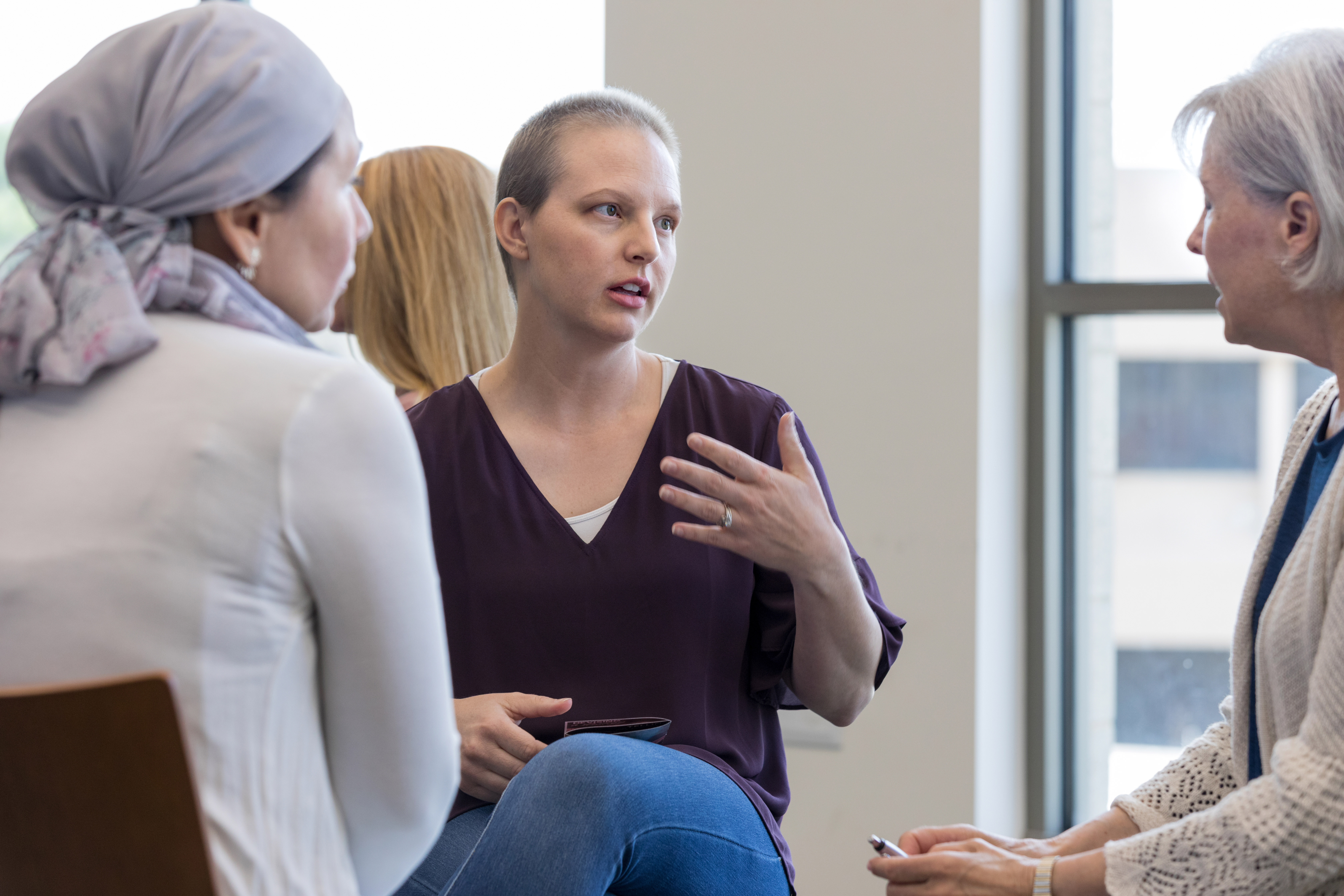Three women sit in a group as one talks about her experience