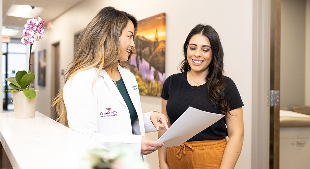 doctor holding a piece of paper and discussing it with another woman