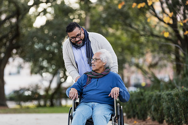 A man leans down to talk to an older man in a wheelchair