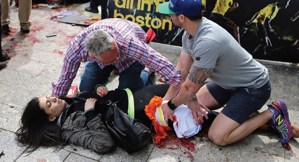 Simulation of a woman bleeding on the ground while passersby attend to her wounds