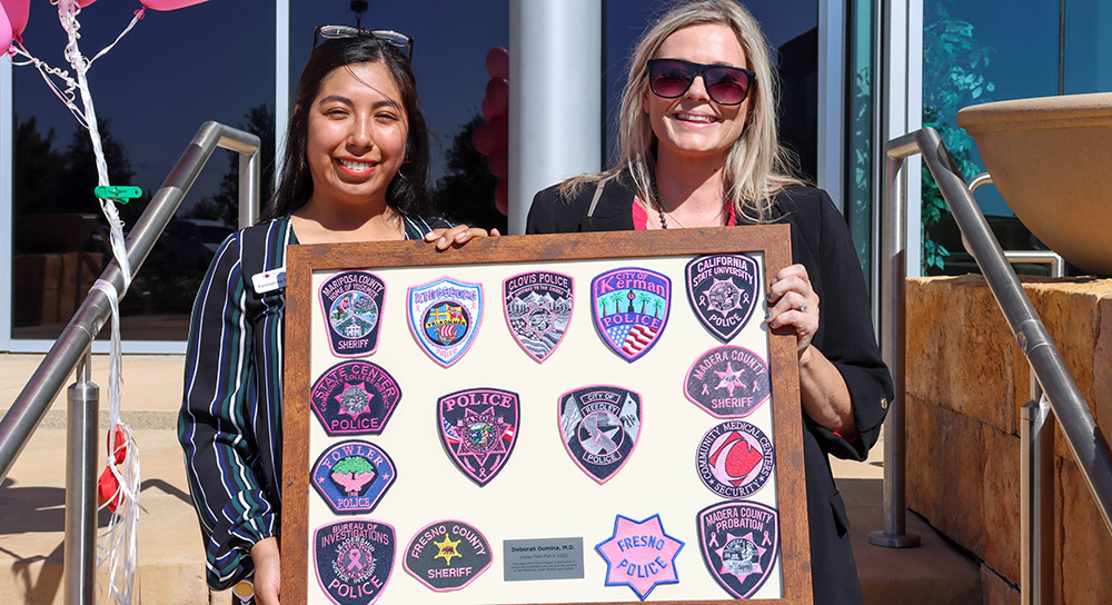 two women holding a framed display of pink patches