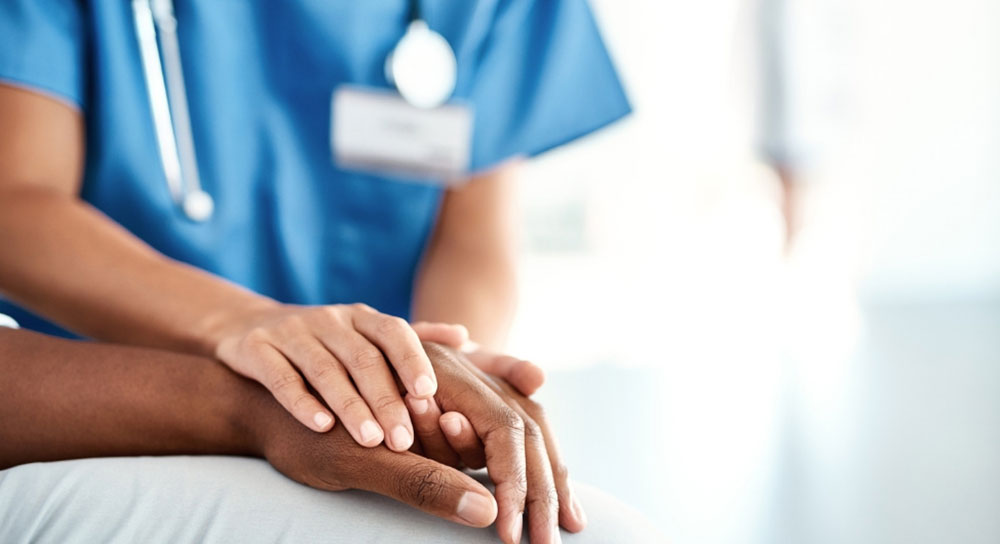 Close-up of a nurse's hands grasping a patient's hands