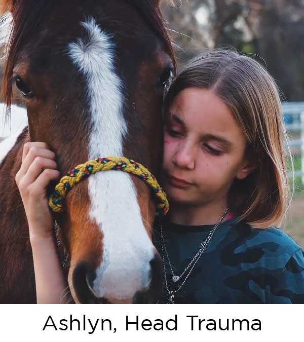 A young girl with dark blond hair, rests her face against the head of a brown horse