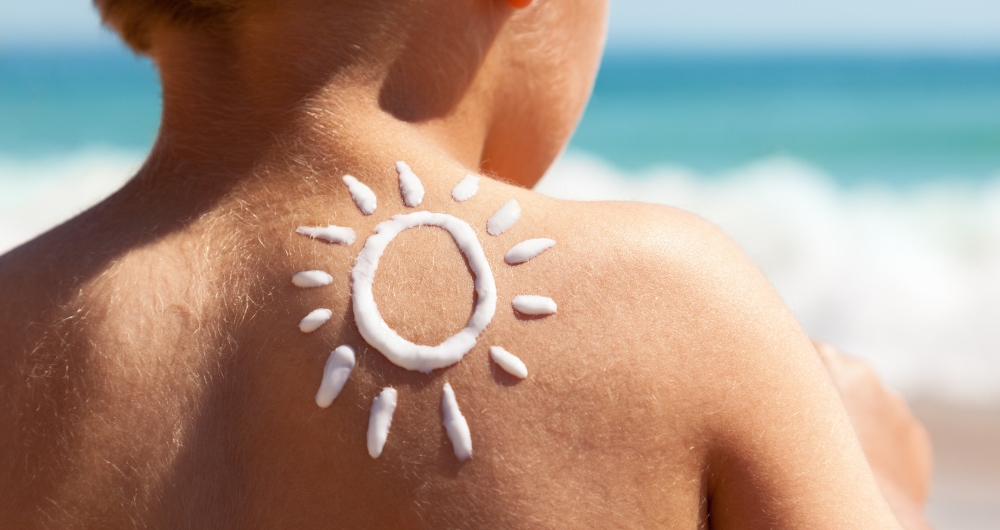 kid with sunscreen in the shape of a sun on his shoulder