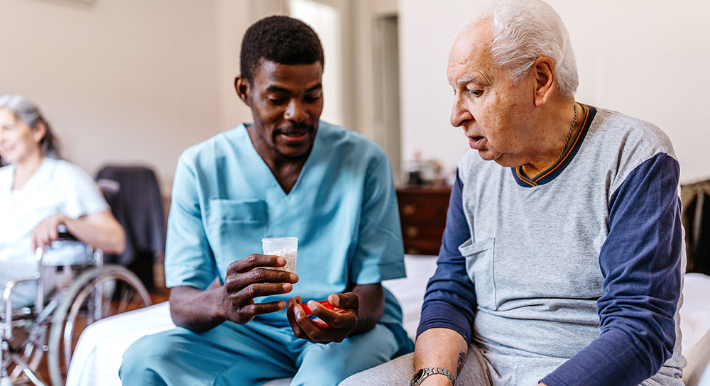 A healthcare worker hands medication to an elderly patient
