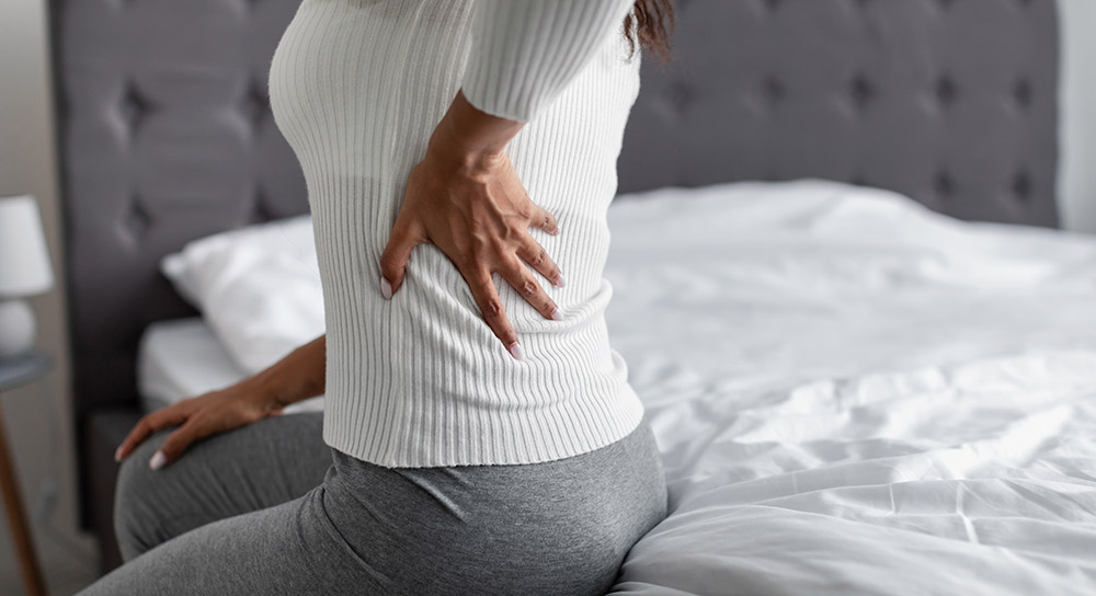A woman holds her mid back in pain