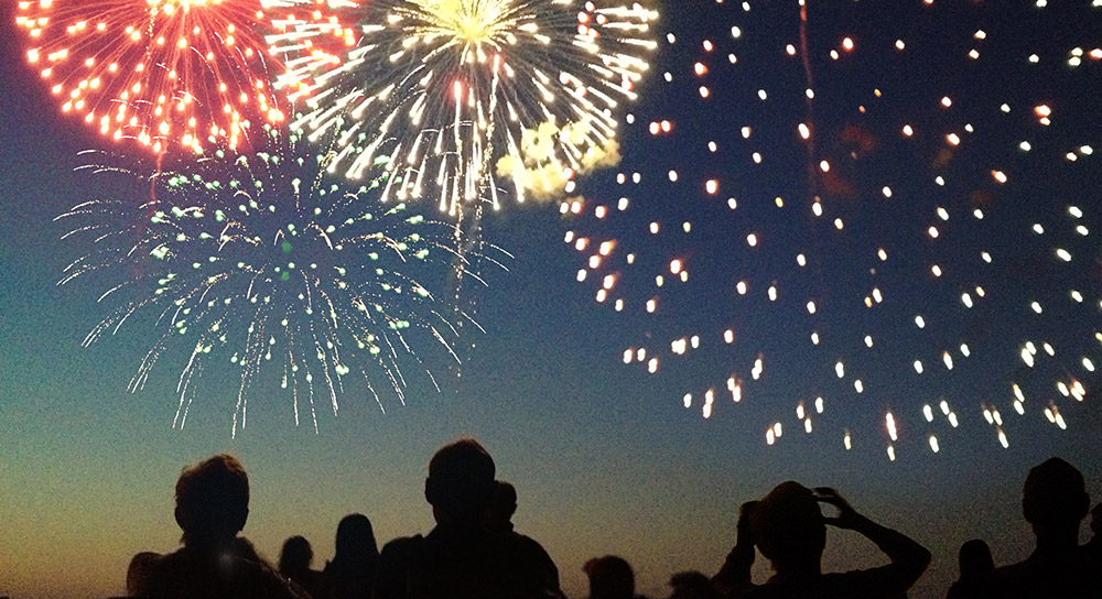 group of people looking into the night sky to watch fireworks