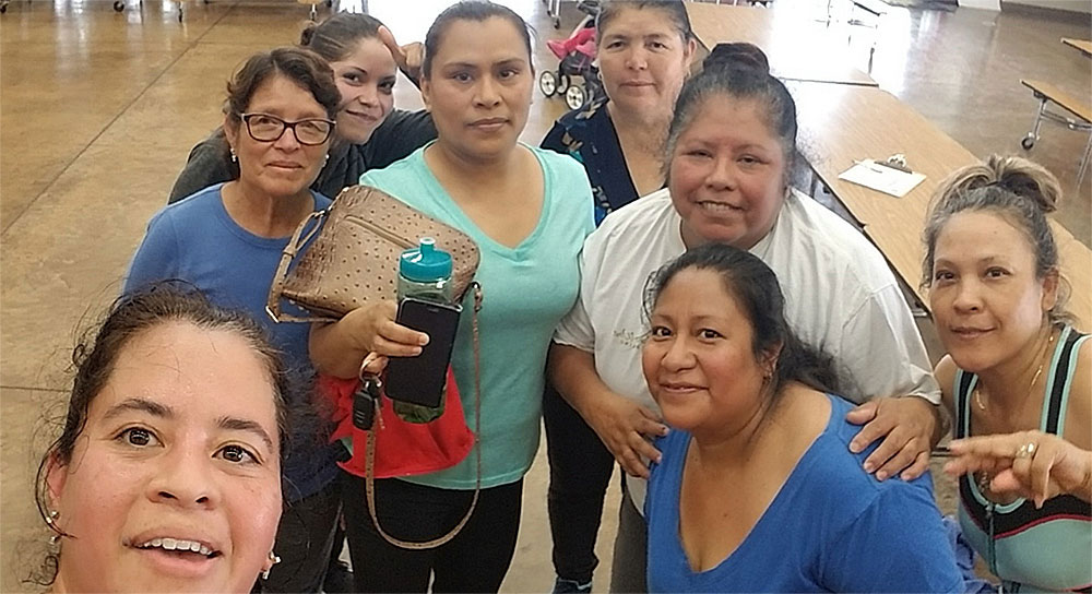 A group of eight Latina women smile at the camera